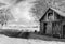 Old abandoned barn with pressed hay and a road across meadow abutting the horizon with clouds