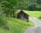 Old abandoned barn on the roadside in a green field