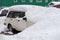 An old abandoned car is buried under a giant snowdrift