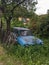 Old abandoned car is deserted on overgrown desolated garden