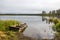 An old abandoned flooded wooden fishing boat is tied with a rope to a wooden snag. Trees are reflected in the rippled surface of