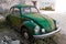 Old abandoned green-coloured classic Volkswagen Beetle.