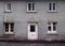 Old abandoned grey derelict house on a residential street with dirty broken windows