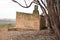 Old abandoned house on farm next to trees.