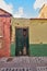 Old abandoned house or home with a weathered green wall and blue wooden door. Vintage and aged residential building