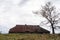 Old abandoned house with a rusty roof. House and tree. Lonely house at the top. Minimalism