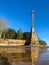 Old abandoned metal rusty lighthouse with a large stone foundation by the sea with a reflection in the water. shore of sandstone