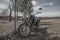 An old abandoned motorcycle stands by the fence.