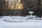 Old abandoned park with fountain. Winter landscape with forest and sunset