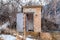 Old abandoned public restroom in the mountain surrounded by leafless brown trees