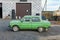 Old abandoned rusted light green colored soviet retro car near the auto repair shop ready for tuning.