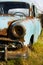 Old, abandoned rusty car wreck front and lamp.