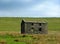 An old abandoned stone farmhouse in green pasture on high pennine moorland with bright blue sky