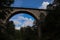 Old abandoned stone railway arch bridge over the river in the forest