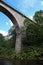 Old abandoned stone railway arch bridge over the river in the forest