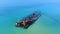 Old abandoned stranded ship lying in clear turquoise sea after crush. Aerial view