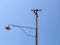 Old abandoned street light with broken wires under blue sky