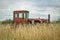 An old abandoned tractor in a field overgrown with tall grass