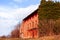 Old abandoned and uninhabited red house typical rural peasant from Friuli surrounded by greenery.