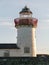 Old abandoned white lighthouse building against a sky background. Nobody. Empty tower with red metal railing