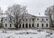 An old abandoned white manor in winter in the snow.