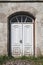 Old abandoned white wooden door in house at town street