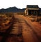 old abandoned wood house in the desert vast landscape. Mountain range in the horizon. Dirt desert road.