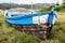 Old abandoned wooden fishing boat stranded on land and grass.