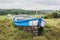 Old abandoned wooden fishing boat stranded on land and grass.