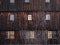 Old abandoned wooden house. Dark brown barn with windows. Weathered house in village. Rural architecture. Aged timber home.