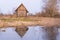 Old abandoned wooden house, a hut in the village with one small window is located near the pond, the house and the blue sky are re