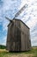 Old abandoned wooden mill and wheat summer field