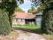 Old abandoned worn down farm country house outside through hedge