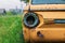 An old abandoned yellow car stands near the fence