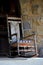 Old Adirondack rocking chair against stone wall