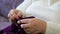 Old adult woman is sitting on the sofa and knitting. Close-up of women`s hands doing handicraft handwork, hobby of adult women in