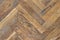 Old aged dirty herringbone parquet background. Natural weathered scratched oak hardwood texture