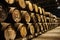 Old aged traditional wooden barrels with wine in a vault lined up in cool and dark cellar in Italy, Porto, Portugal, France