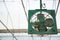 Old aged vintage retro rustic green indoor ceiling mechanical metal fan blower for air ventilation, temperature cooling control