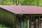 Old aged and weathered little farmhouse shed on a green field