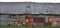 Old aged weathered wooden shack, grey plated wood boarding hut wall, patched planks, rusted metal plates, rusty paint texture