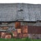 Old aged weathered wooden shack, grey plated wood boarding hut wall, patched planks, rusted metal plates, rusty paint texture