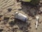 Old aluminum beer can and plastic fork on a sandy beach, ecology issue and problem