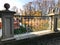 Old ancient vintage beautiful stone wrought iron railing of a bridge with patterns on the background of the river and trees