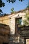 Old ancient yellow destroyed stone house on the yard with trees around. Poverty and misery, South, summer