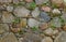 Old anticient stone wall from rough rocks with moss and wild plants, background, texture