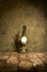 Old, antique oil lamp burning on rustic tiles with concrete wall background