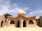 An old antique sturdy small stone beige building with a round roof in an Arab Muslim Islamic warm tropical country in the desert