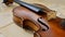 An old antique violin on a table with yellowed sheet music.