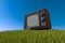 Old antique wooden TV on grassy hill